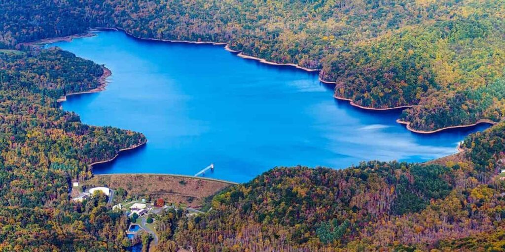 Aerial view of the North Fork Reservoir NC, surrounded by dense forest with clear blue water, showing potential for floating solar panel installation.