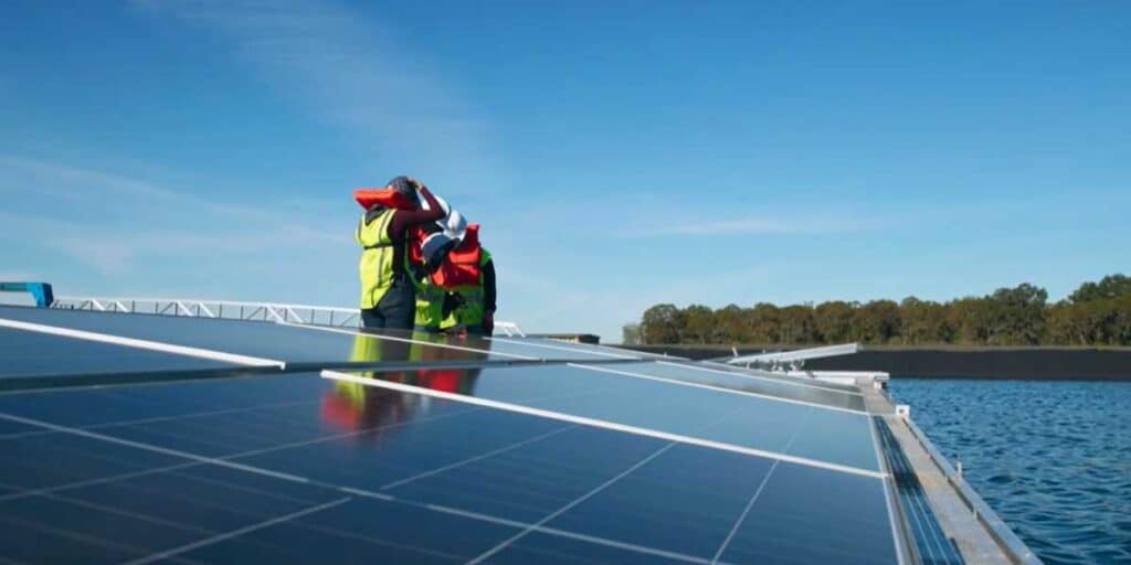 Technician inspecting floating solar panels on a water-based solar installation