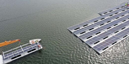 Workers assembling floating solar panels on water during Floating Solar Farm Construction, showing installation process and system setup.