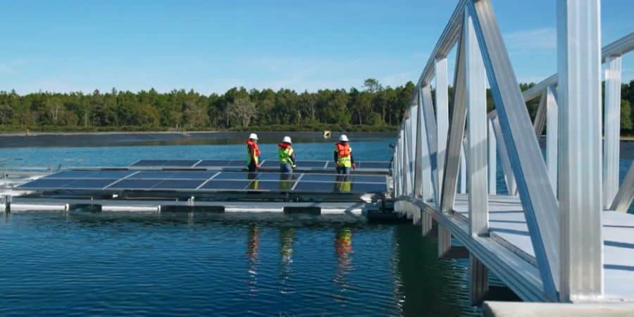 Technicians working on a floating solar installation near a reservoir platform