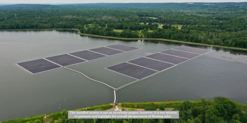 Aerial view of floating solar on reservoirs with multiple panel arrays connected by walkways, surrounded by forested landscape, demonstrating renewable energy and water conservation solutions