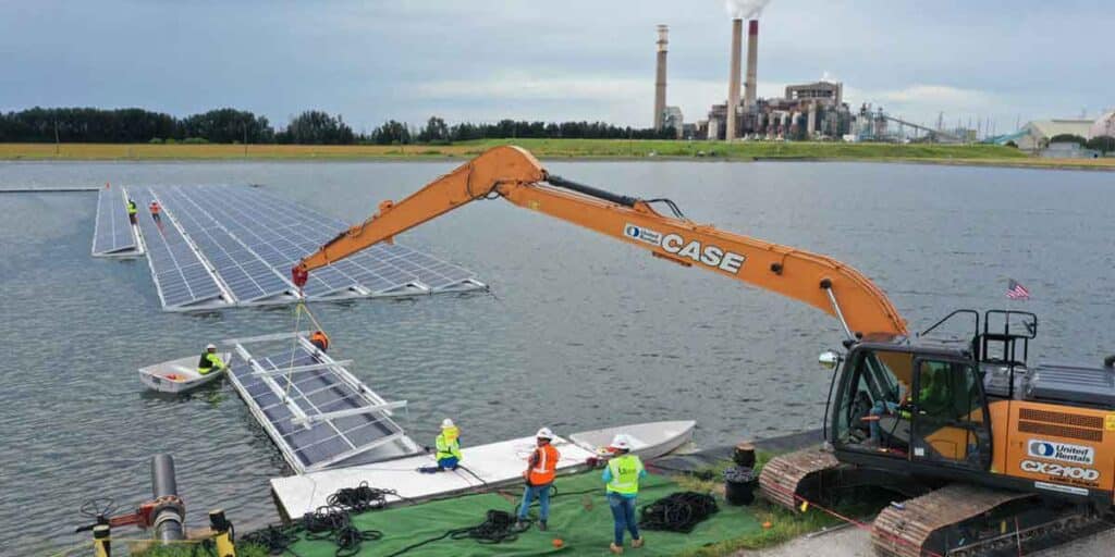 Construction team installing floating solar panels on a water body with the aid of a crane, highlighting the importance of bathymetric maps in determining site suitability and anchoring solutions.