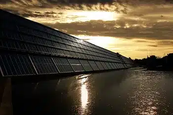 Solar Panels next to water with bright sky with sun